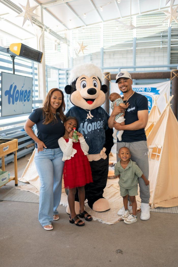 A family posing with Drip the Honee mascot